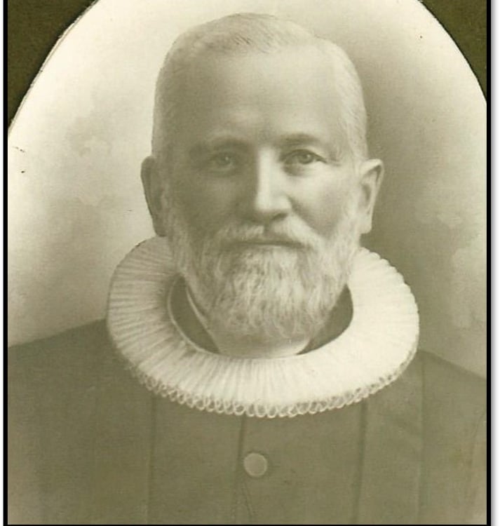 A man with a white ruffled collar and a white beard and mustache, black and white