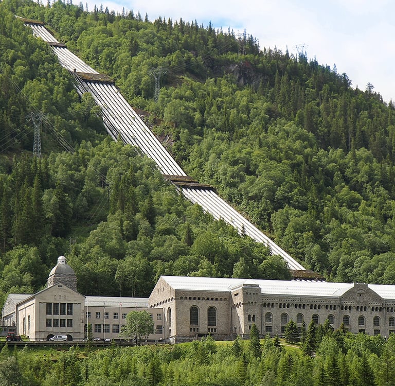 A large industrial building sits at the base of a green slope-NIA used with permission