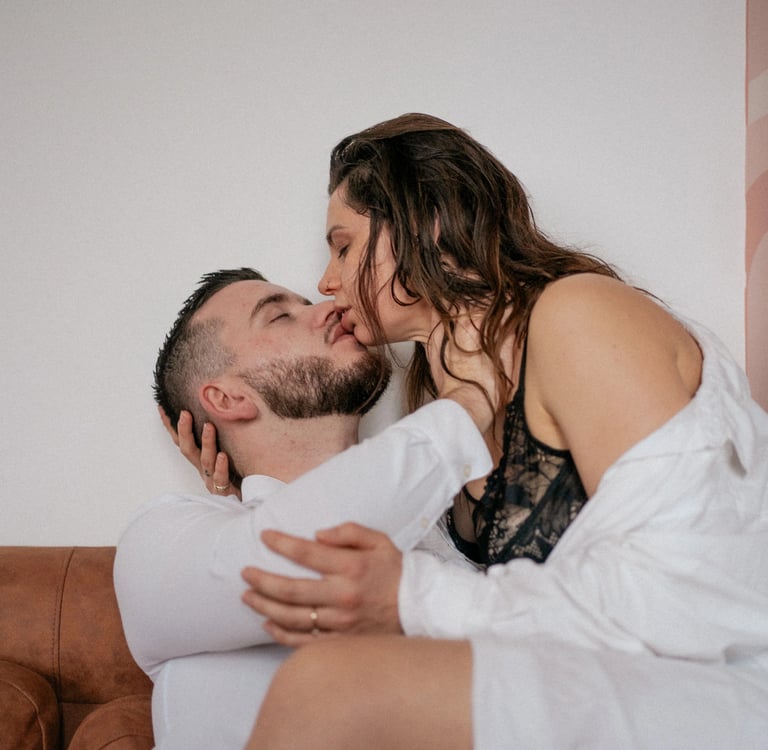 Couple s’embrassant sur un canapé en cuir lors d’une séance photo de couple intimiste à Rennes.