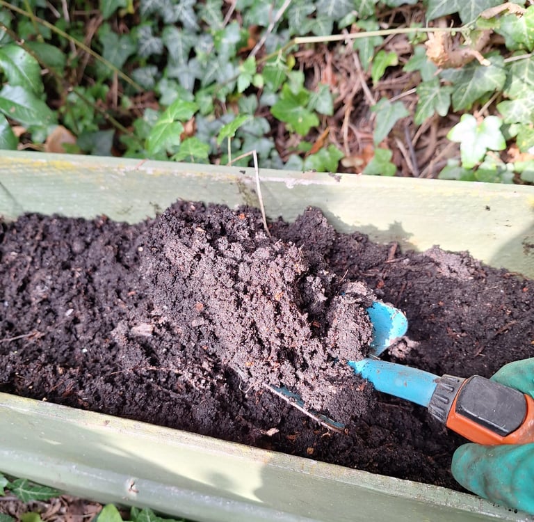 a person that is fertilizing garden bed soil