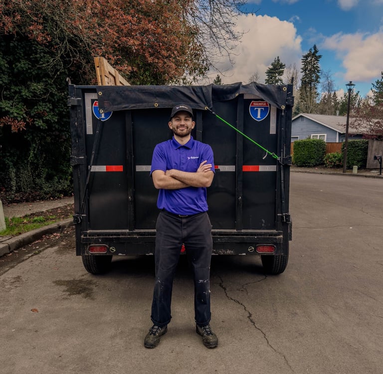 Professional junk removal service worker standing in front of a black dump trailer in Portland OR