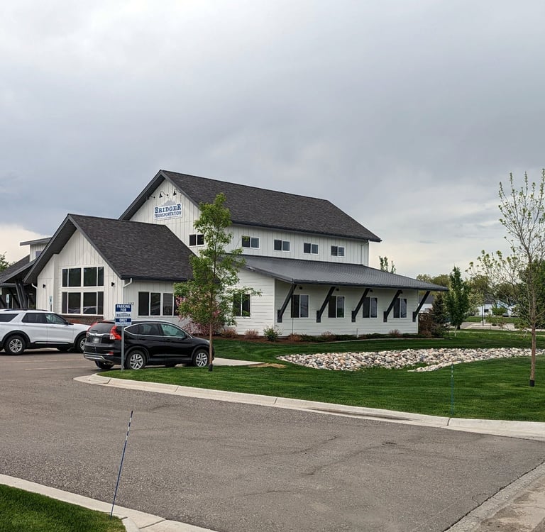 a white house with a black roof and a white car parked in front of it
