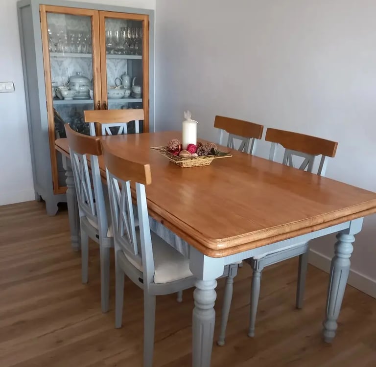 una mesa color madera y cinco sillas color gris con una vitrina de fondo del mismo color