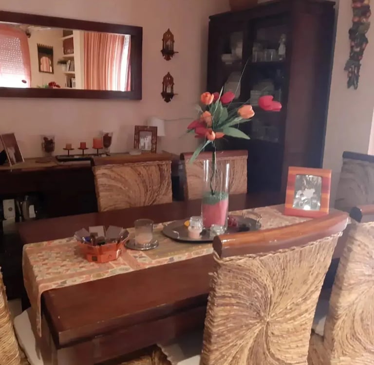 mesa de madera con cuatro sillas de madera una comoda y un espejo