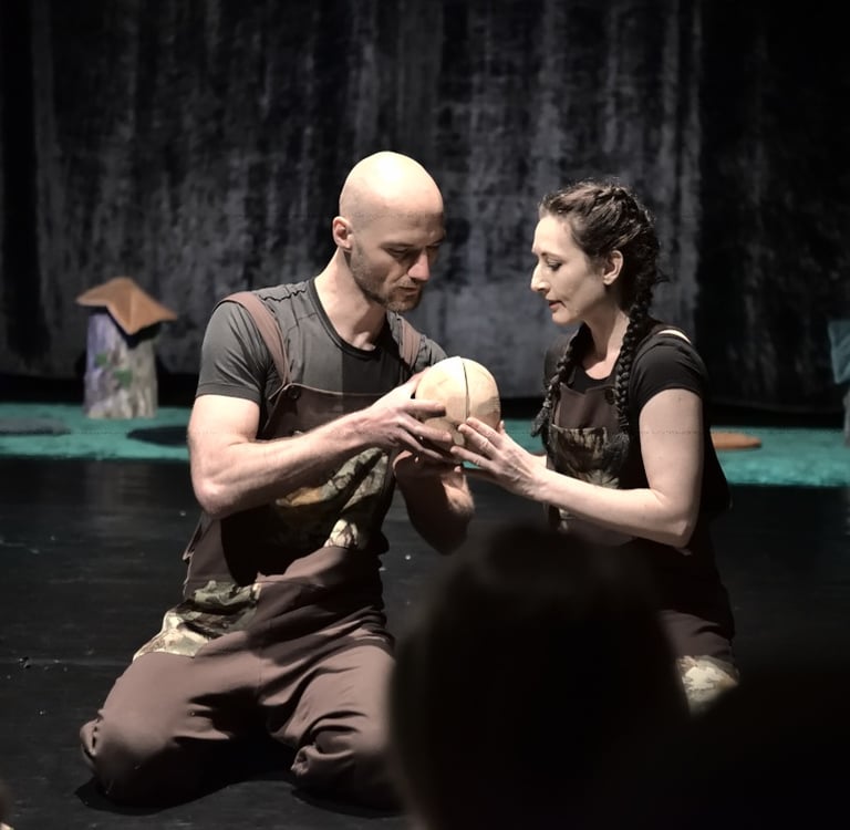 Mężczyzna i kobieta na scenie obserwują drewniane kule.