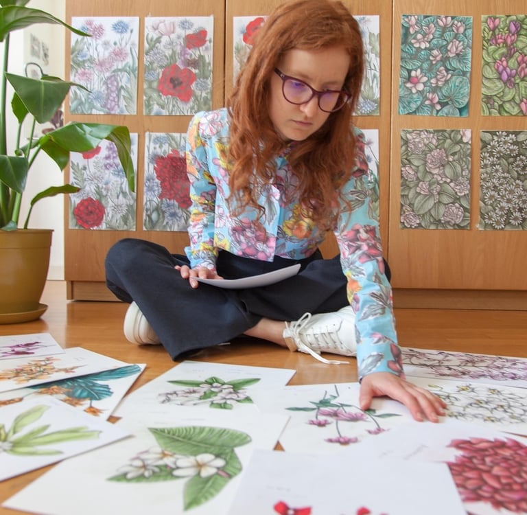 A Woman sat on the floor surrounded by botanical illustrations