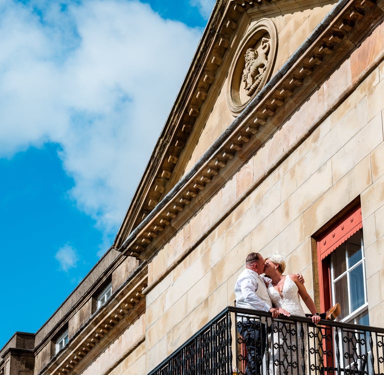 a bride and groom kissing on a balcony balcony