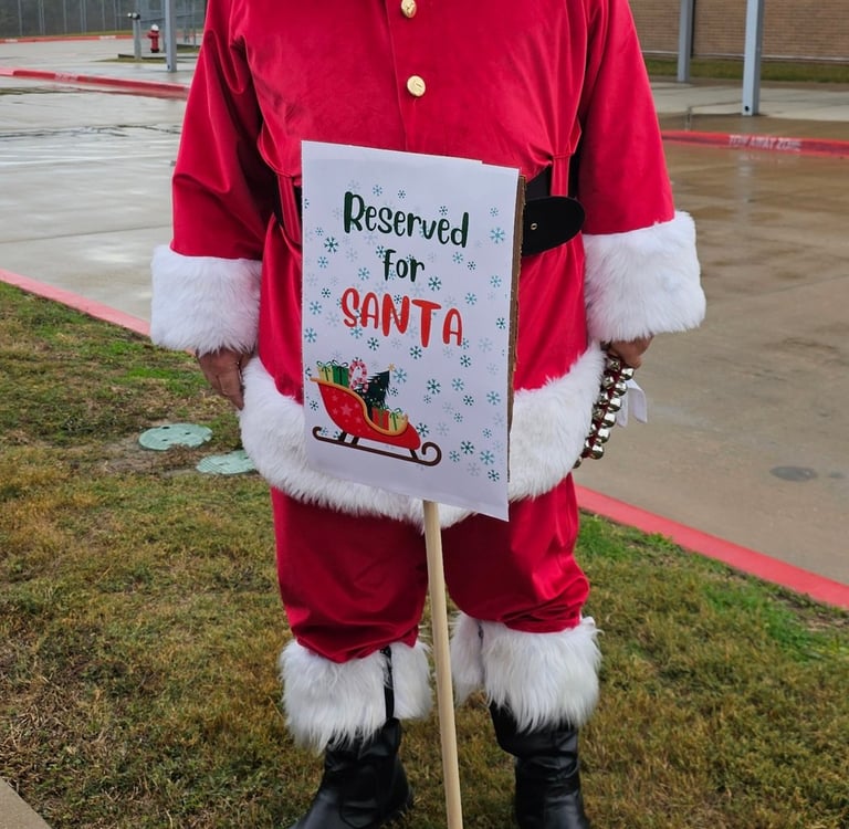 The Santa Cowboy standing behind his "reserved " parking sing at Spring Creek Elemtary school visit