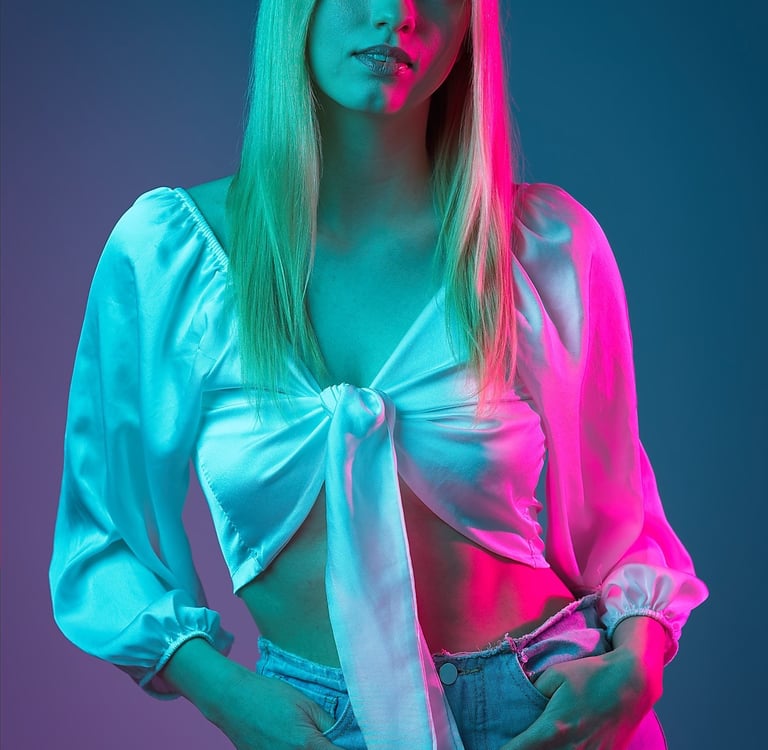 Portrait einer Frau mit weißer Bluse und Jeans vor farbig beleuchtetem Hintergrund