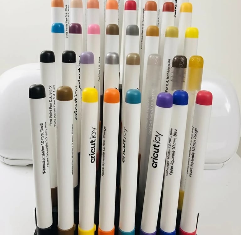 A collection of colorful Cricut Joy watercolor markers and fine point pens in a vertical storage organizer.