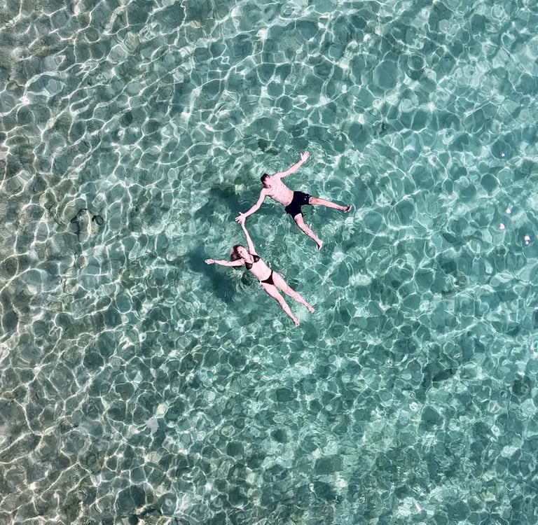 Couple floating in angel positions hand in hand in crystal clear Adriatic water captured by drone