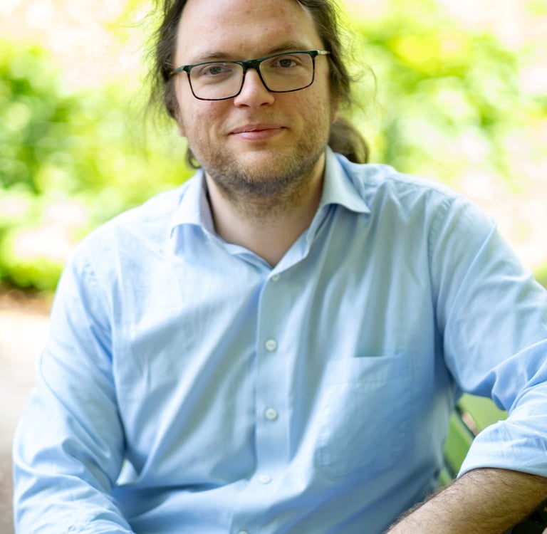 Jelle Dehaen, een therapeut met wat langer haar en een bril. Hij is rustig en vertrouwensvol.