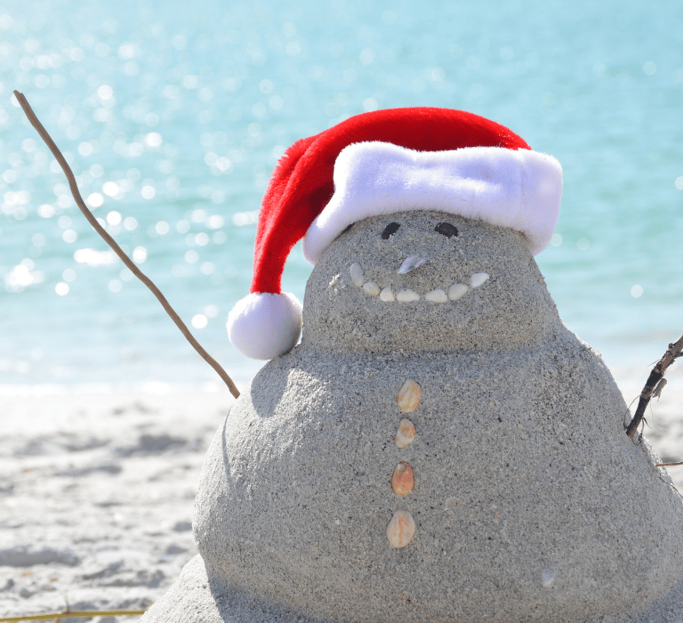 beach snowman made of sand with santa hat