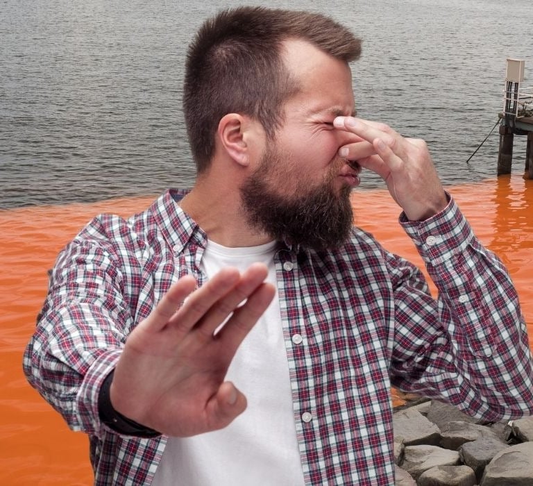 man holding nose from smelly red tide odor