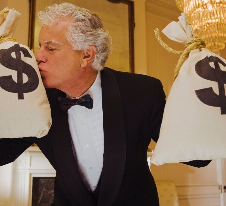 man in tuxedo kissing bags of money