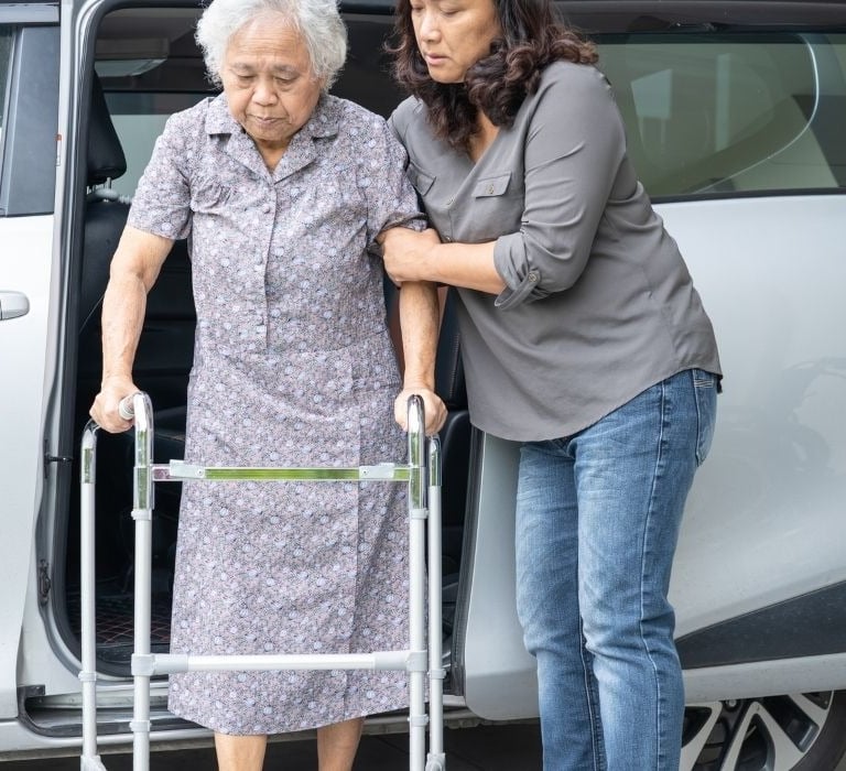 senior asian woman with walker helped by younger woman