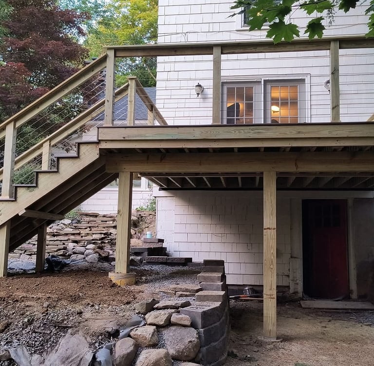 Custom wood deck with outdoor seating overlooking a wooded backyard landscape