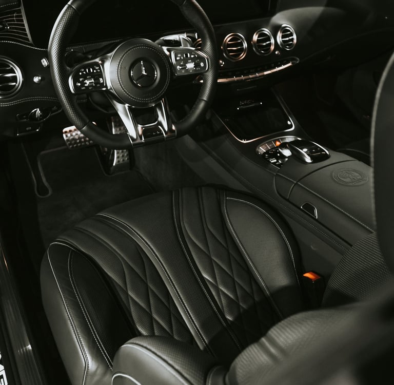Luxury black leather interior of a Mercedes-AMG with quilted seats and a sport steering wheel.
