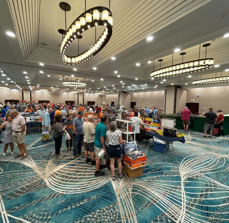 Collectors browsing model trains and layouts at a busy East Coast model train show.