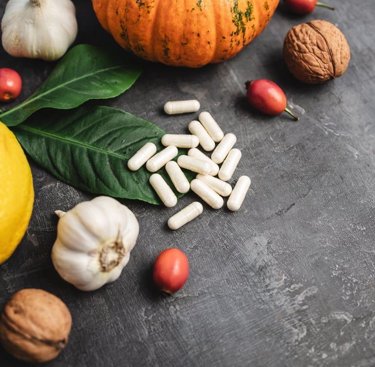 supplement pills, head of garlic, spinach leaf, lemon, and other fruits and vegetables on a table