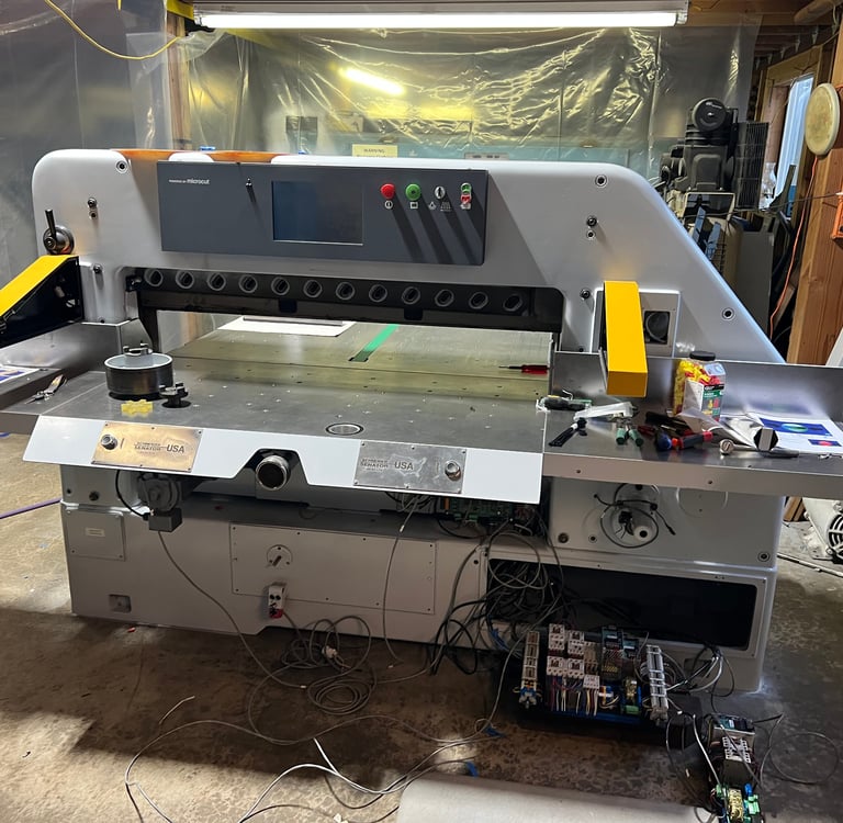 Two stainless steel laser engraved cut button covers installed on a guillotine paper cutter