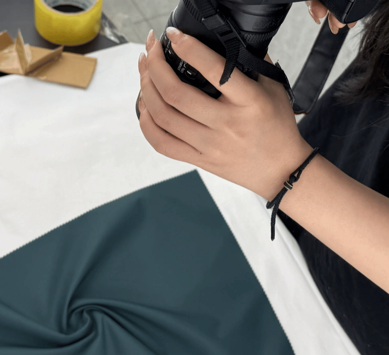 Photographer shooting YL fabric in deep blue velvet on a white table with a DSLR camera.