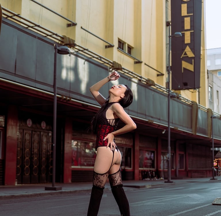 A model in a red corset and black lace stockings poses outside the Metropolitan theater.