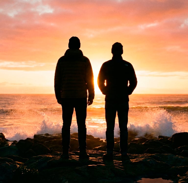 Duas pessoas olham para o nascer do sol sobre as ondas do mar.