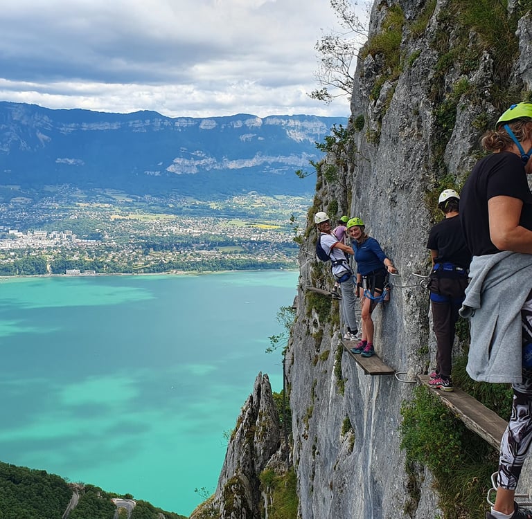 Personnes sur une planche étroite surplombant le lac du Bourget dans la via ferrata du Cornillon