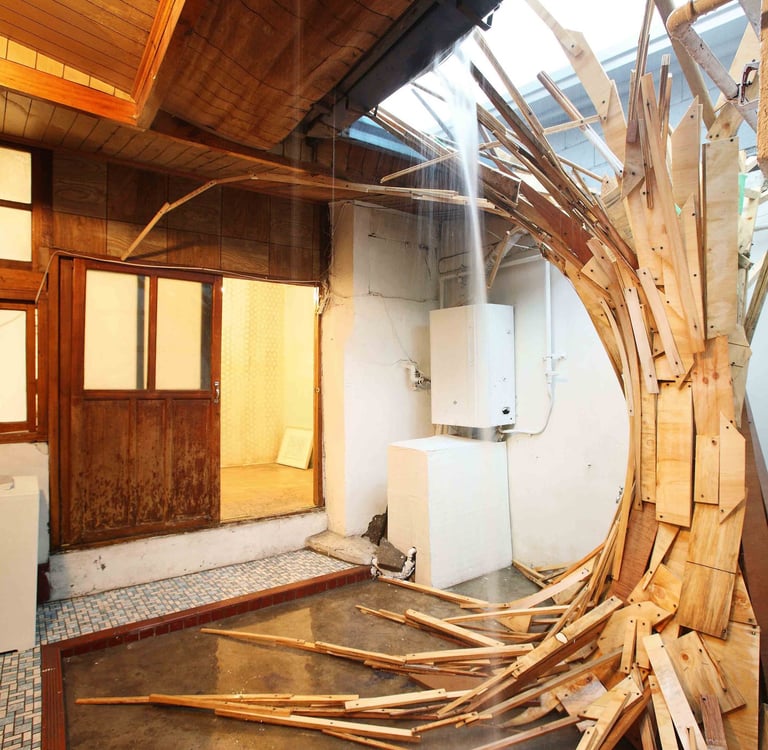 Indoor wooden plank art installation spiraling into a skylight with natural light.