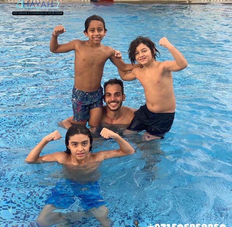 A group of boys and their swimming coach smiling and flexing muscles in an outdoor swimming pool.