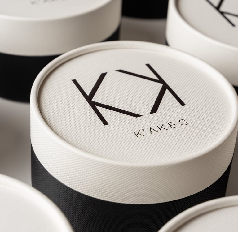 Elegant round black and white K'AKES luxury bakery boxes with minimalist logo branding.