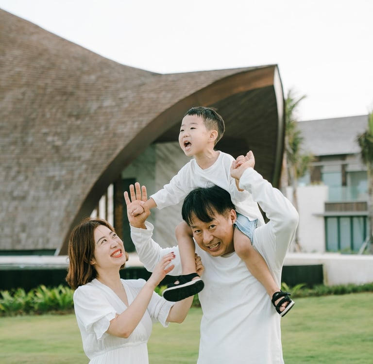 Luxury family photographer in Bali capturing a joyful father lifting his child at The Apurva Kempinski Bali.
