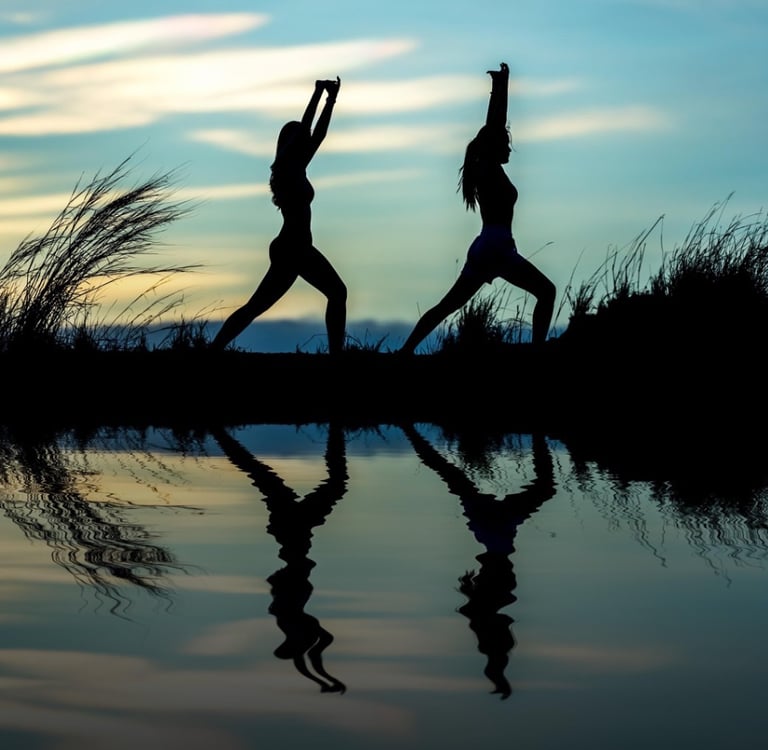 two people doing yoga poses in the evening