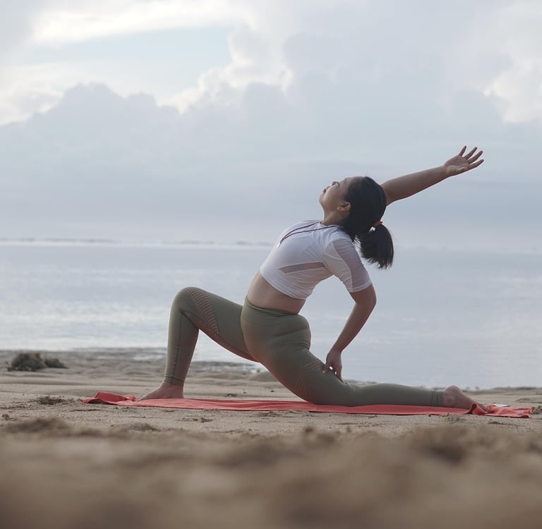 Woman stretching on a beach at sunrise, practicing active recovery with yoga to promote muscle flex