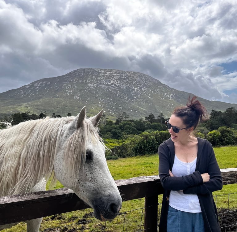 a woman standing next to a horse in a field