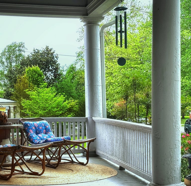 Front porch with lounger chairs and wind chimes 2123 Rivermont apartments