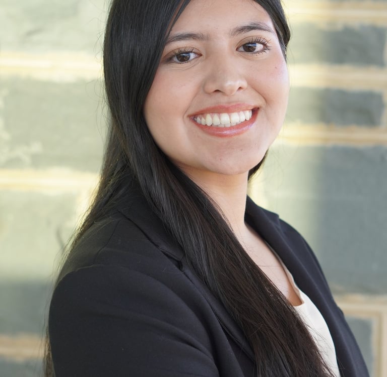 Smiling professional woman with long dark hair wearing a black blazer in a business headshot.