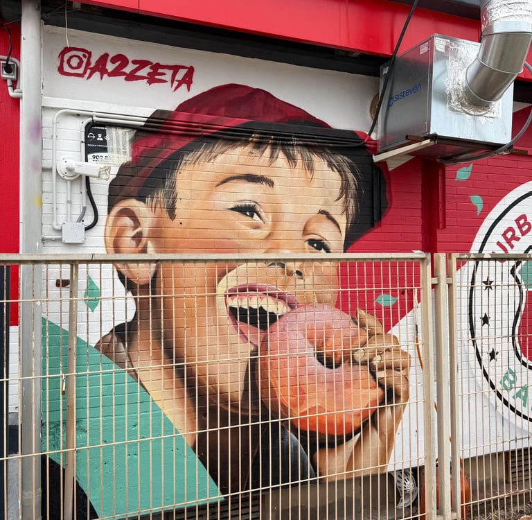 Mural de gran formato sobre fachada urbana realizado con aerosol. Representación figurativa que comb