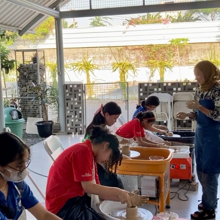 a group of students shaping out clay on pottery wheels