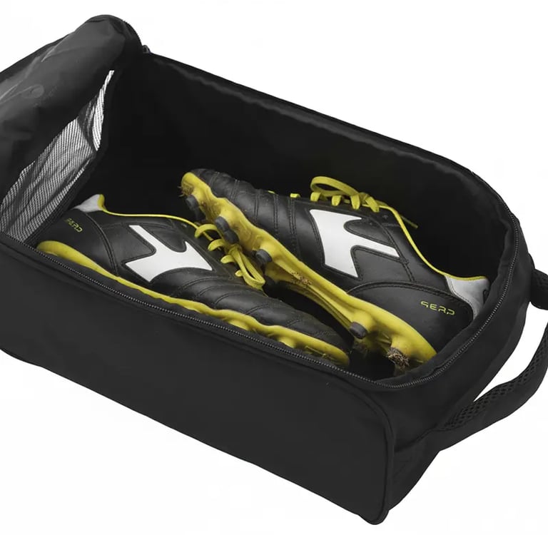 Black and yellow soccer cleats stored inside a black portable sports shoe bag with a mesh pocket.