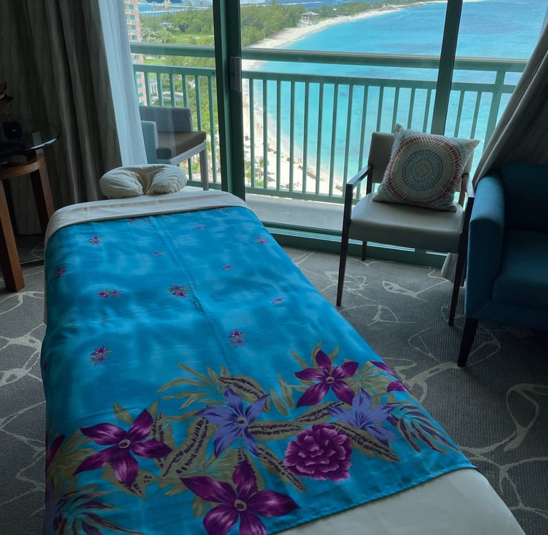 a hotel room with a view of the ocean and a massages by sophia massage table