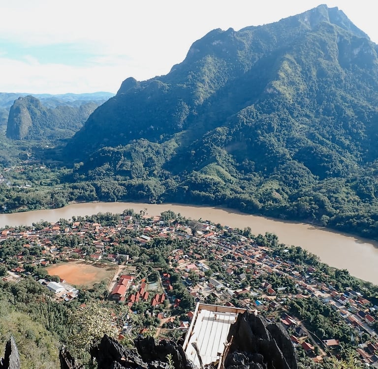 a mountain view of a town with a river and mountains in the background