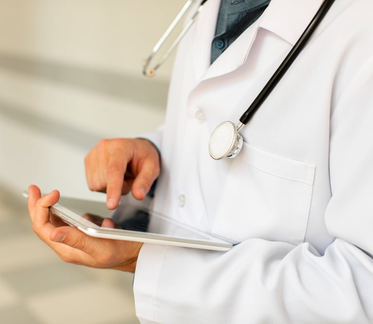A doctor in a white lab coat using a digital tablet for healthcare data and patient records.