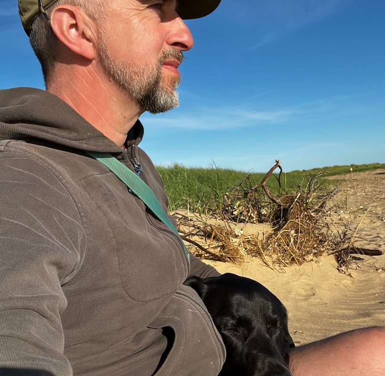 a man sitting on a beach with a dog