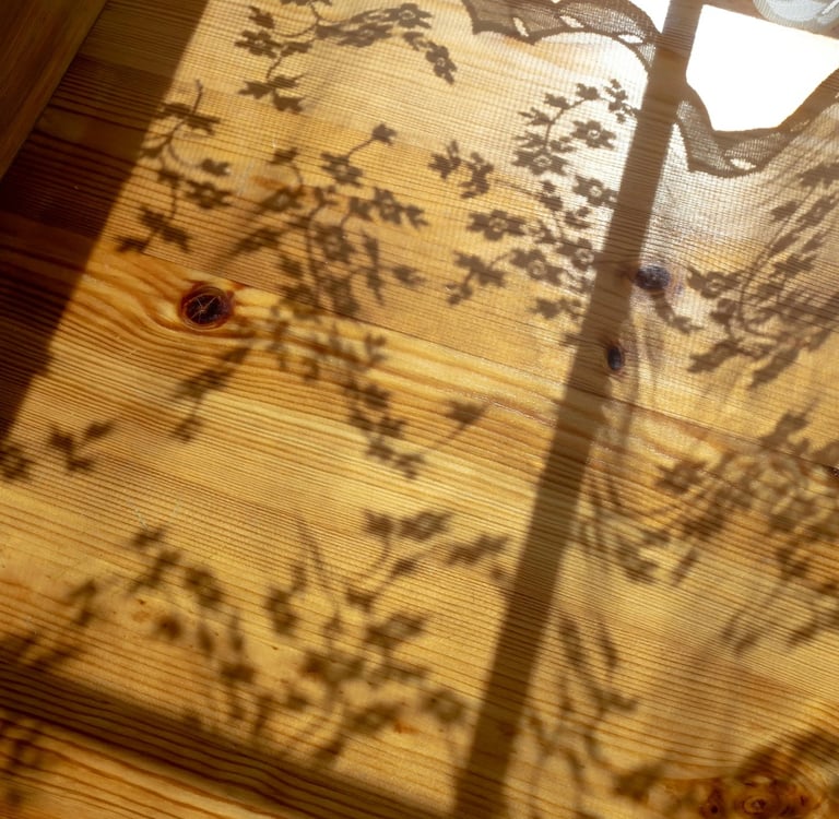 Soft sunlight casting curtain shadows, capturing Jahida's childhood memory of magical sunlit dust.
