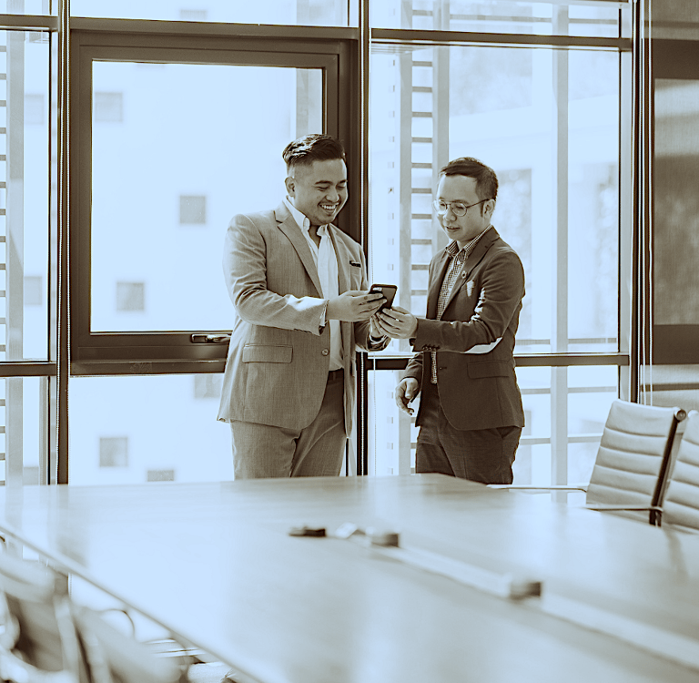 Two engineers in suits looking at a Production Plan in a conference room.