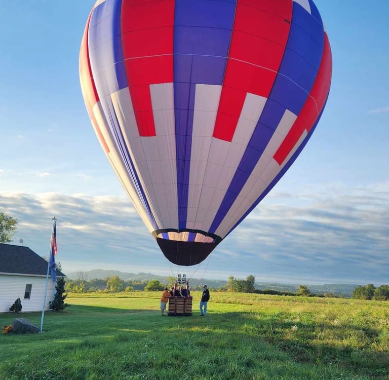a hot air balloon in a field with people standing around