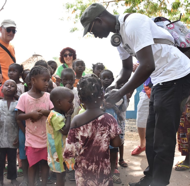 Dahomey African Tours Guide leading Tourists and giving gifts to Children in Senegal