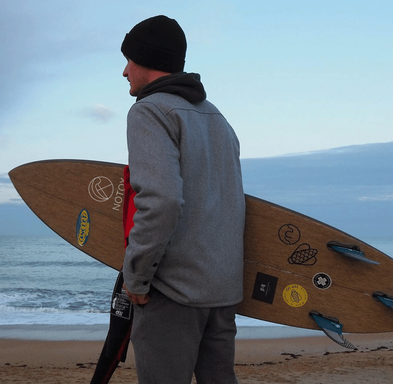 a man in a gray jacket and a surfboard